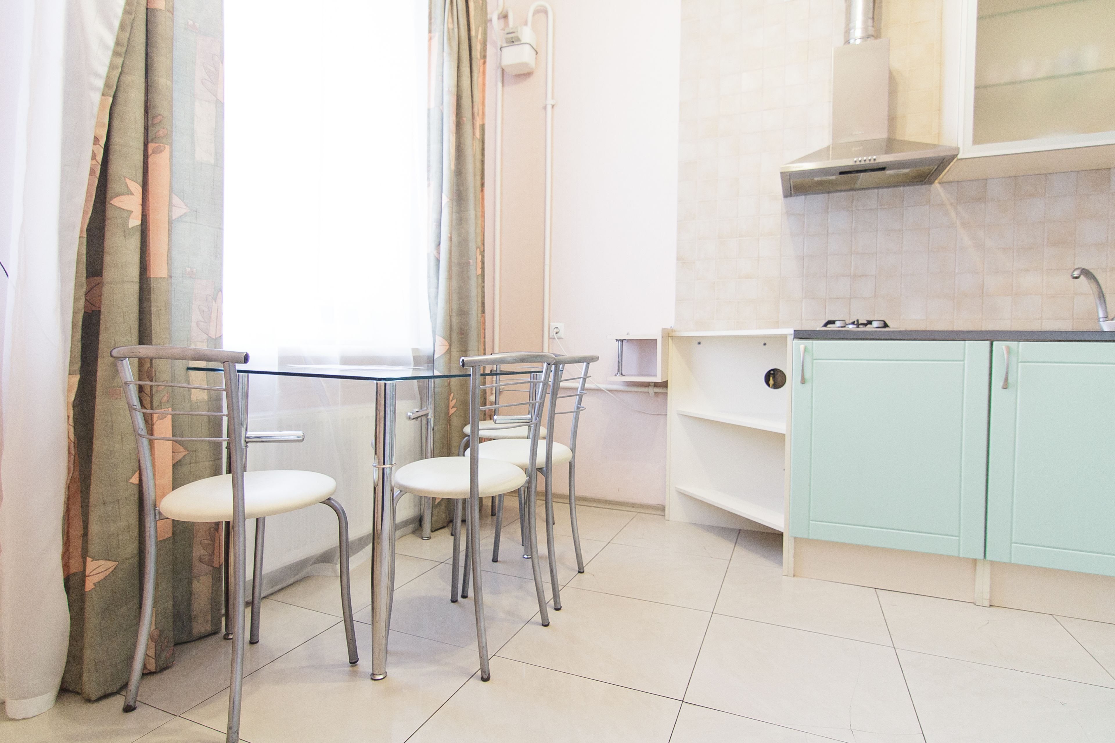 A kitchen with a dining table and chairs, a sink, and cabinets.