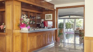 A wooden bar area with shelves of bottles and glasses, a red cooler, and a framed picture on the wall. - Hotel Tre Laghi (Nebbiuno)