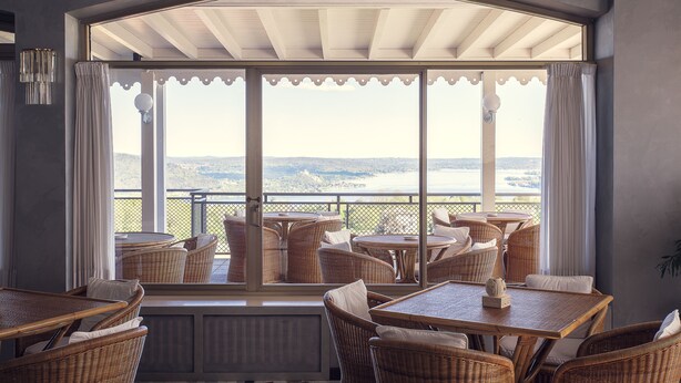 A balcony with wicker furniture and a view of a body of water. - Hotel Tre Laghi (Nebbiuno)