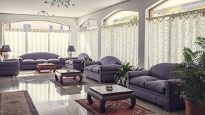 A spacious living room with a large window, a sofa set, a coffee table, and a potted plant. - Hotel Tre Laghi (Nebbiuno)