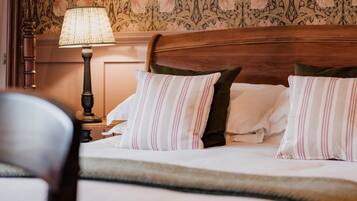 A neatly made bed with striped pillows, a wooden headboard, and a lamp on a nightstand.