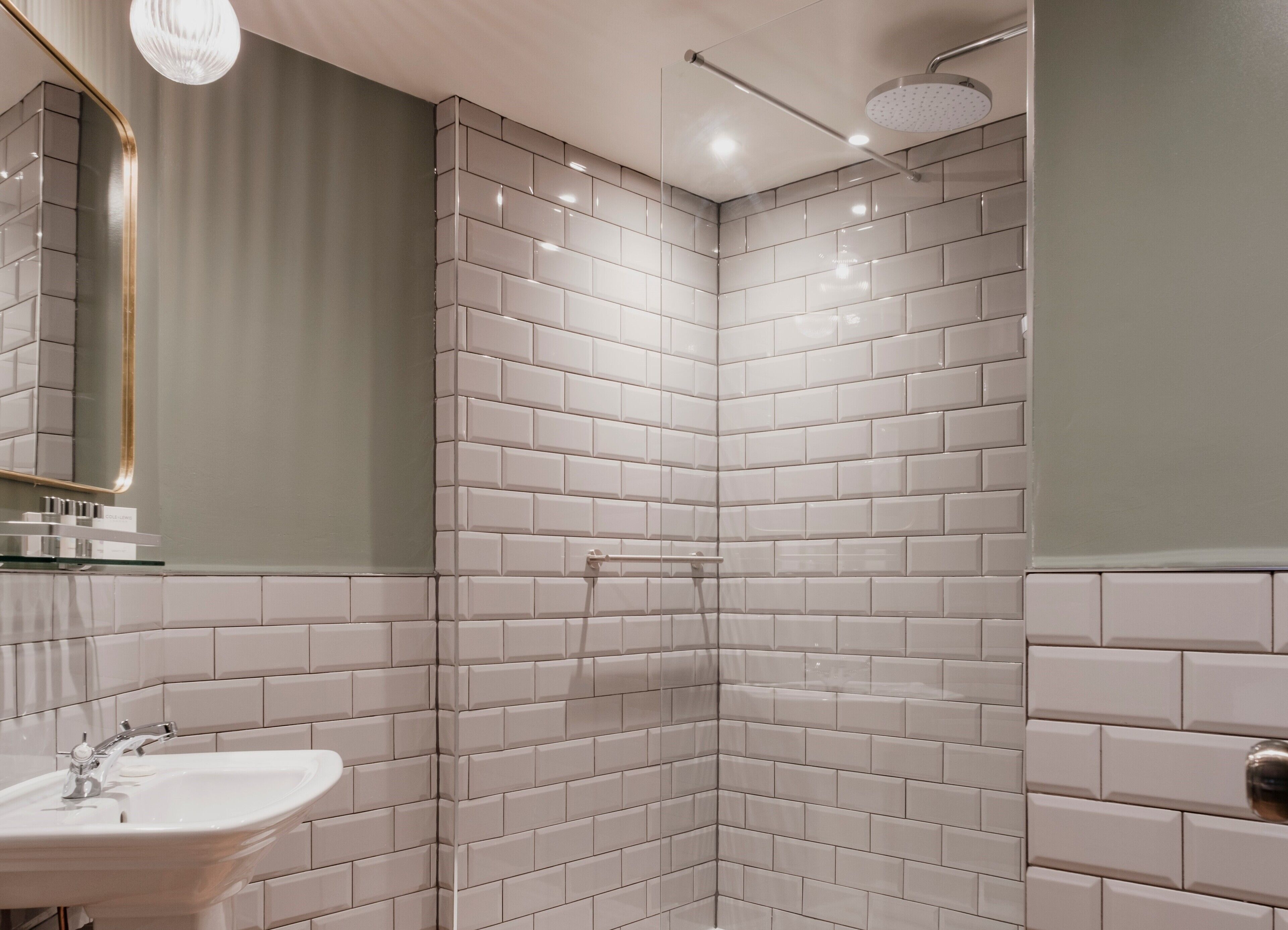 Een moderne badkamer met witte metrotegels, een glazen douchecabine en een wastafelmeubel met een spiegel.