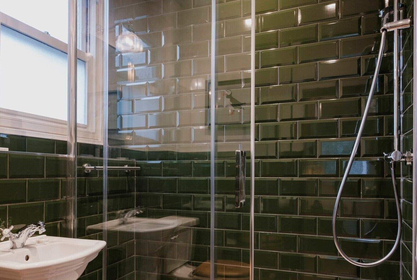 Un baño con cabina de ducha de vidrio, lavamanos y espejo.