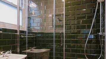 Un baño con cabina de ducha de vidrio, lavamanos y espejo.