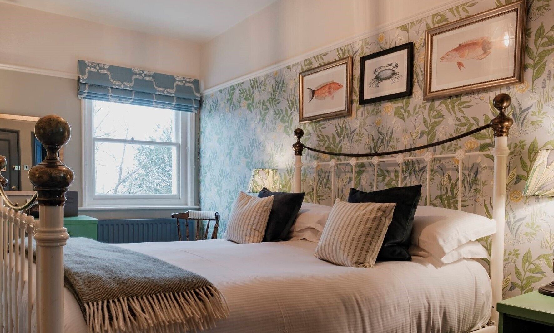 A bedroom with a bed, a window with a view, a radiator, and a curtain.