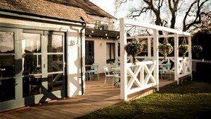 A patio area with outdoor seating and hanging flower baskets. - The Fisherman's Haunt (Christchurch)