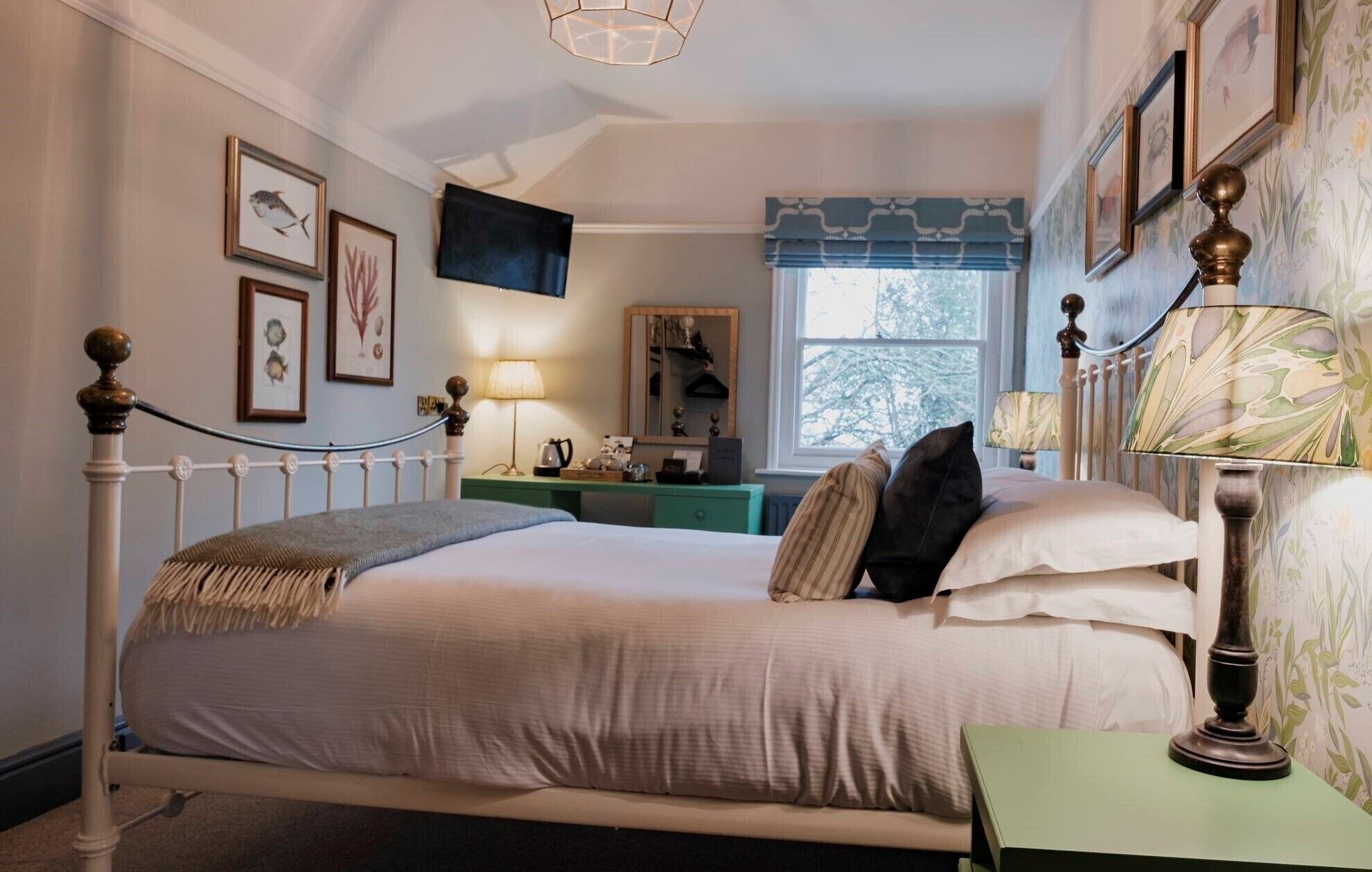 A neatly arranged bedroom with a bed, bedside table, lamp, and a dresser.