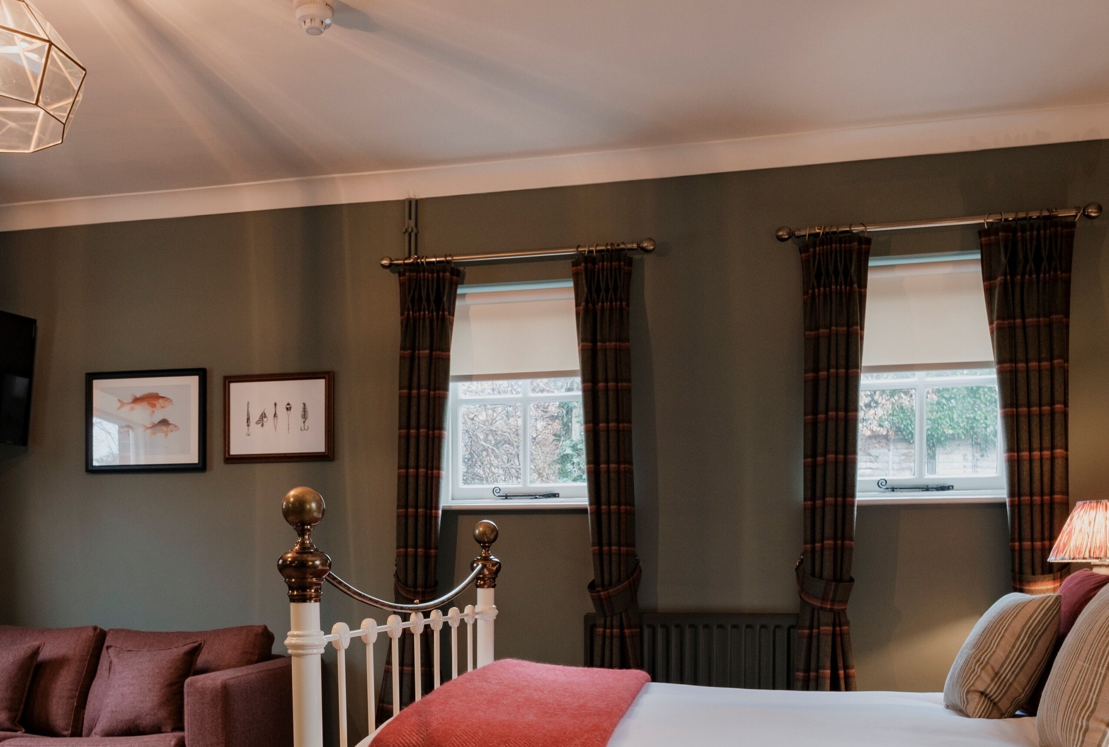 Une chambre à coucher avec un lit, une table de chevet, une lampe, une fenêtre avec des rideaux et un radiateur.