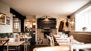 A restaurant with wooden tables and chairs, a brick fireplace, and a chalkboard menu. - The Fisherman's Haunt (Christchurch)