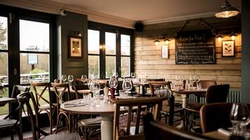 A restaurant with wooden walls, multiple tables, and chairs, and a chalkboard menu on the wall.