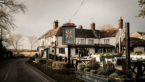 A traditional pub with a sign reading "The Fisherman's Arms" and an entrance sign stating "Entrance 100 Yards". - The Fisherman's Haunt (Christchurch)