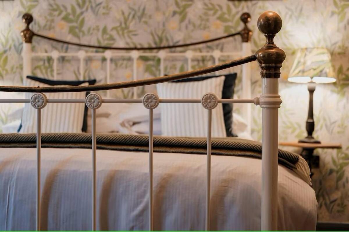 Un lit avec une tête de lit en métal et une lampe décorative placée à côté.
