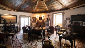 A spacious room with a high ceiling, a fireplace, and a dining area with chairs and a table. - Casa do Redondo (Meda)