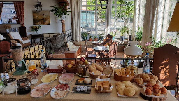 A breakfast buffet with various food items, a coffee machine, and a view of the garden through large windows. - Casa do Redondo (Meda)