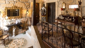 A rustic interior with stone walls, a wooden staircase, and a metal railing. - Casa do Redondo (Meda)