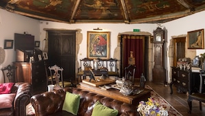 A room with a high, ornate ceiling, a brown leather sofa, a wooden cabinet, and a painting on the wall. - Casa do Redondo (Meda)