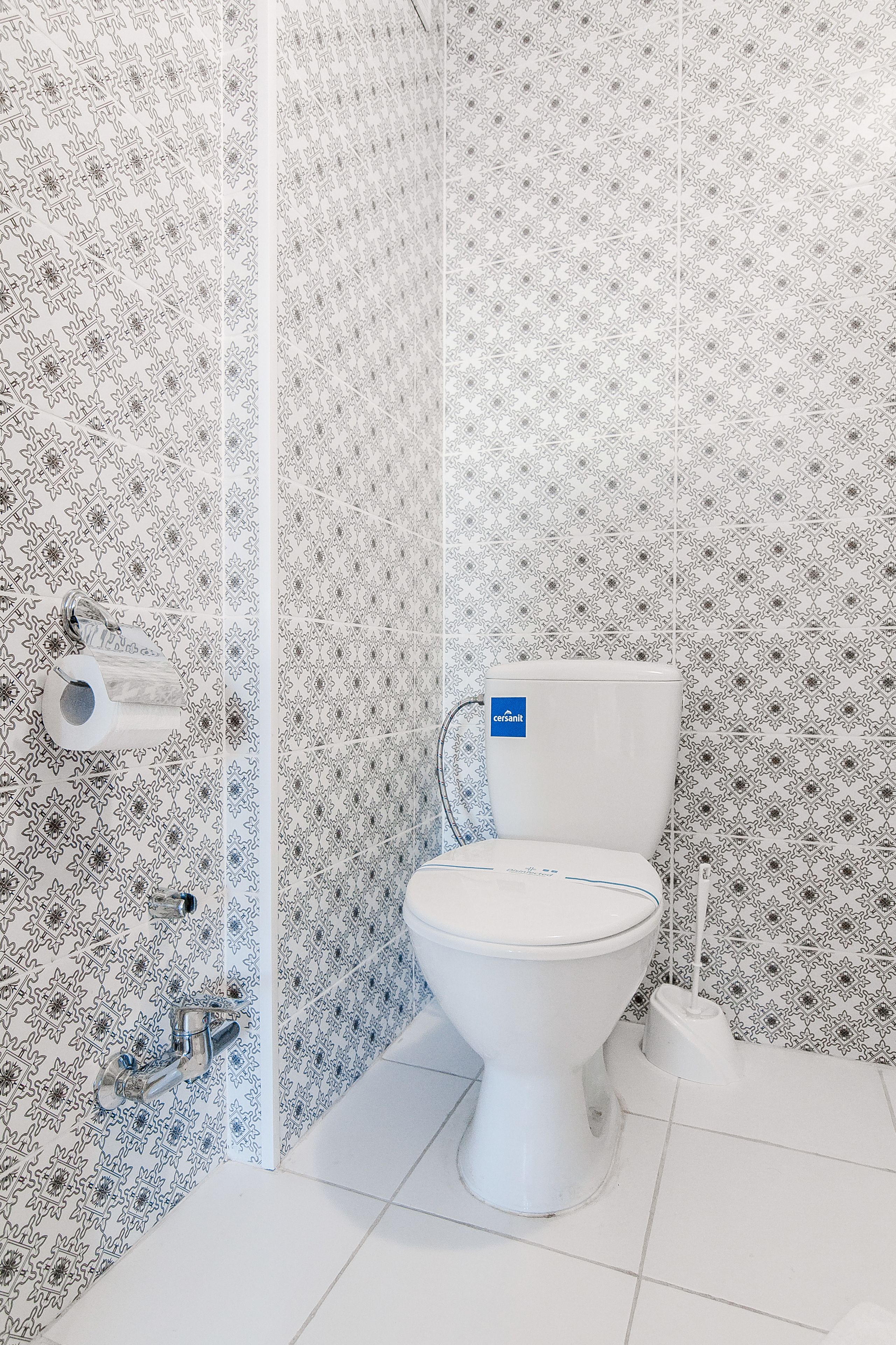 Une salle de bain équipée de toilettes, d’un porte-rouleau de papier toilette et d’un bidet.