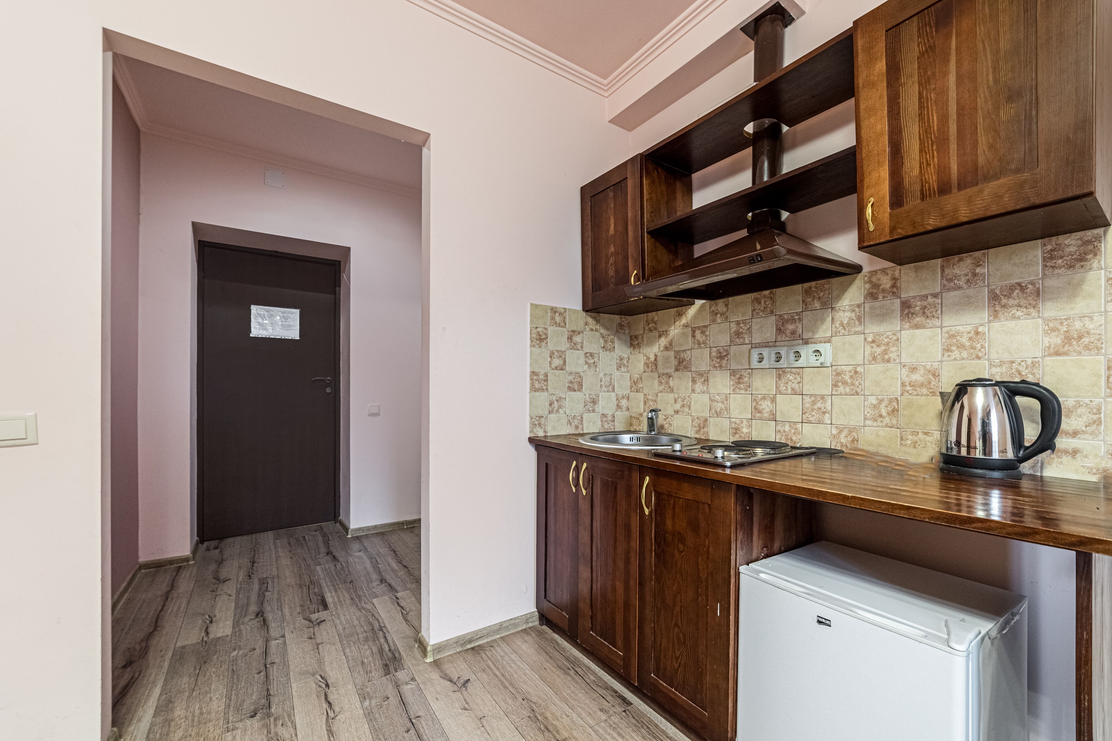 Una cocina compacta con armarios de madera, un refrigerador blanco y un salpicadero de azulejos.