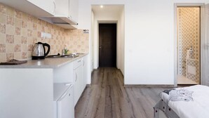A compact kitchen with white cabinets, a kettle, and a tiled backsplash. - Odessa Rent Service Apartments at Sea-side (Odesa)