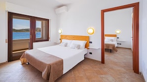 A bedroom with a bed, a view of the sea, and a wooden door. - Hotel Il Gabbiano (La Maddalena)