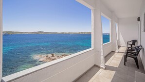 A balcony with a view of the sea, a chair, and a tiled floor. - Hotel Il Gabbiano (La Maddalena)