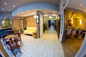 A modern interior with a dining area, a sofa, and a small table with chairs. - Hotel Restaurant Les Edelweiss (Cauterets)