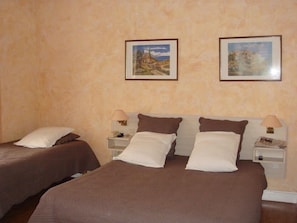 Ett hotellrum med två separata sängar, var och en med en kudde och ett sängbord med en lampa.