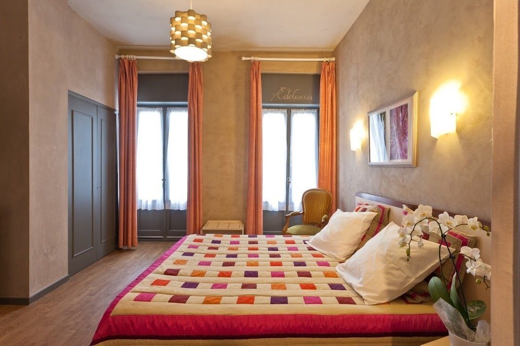 Una habitación de hotel con una cama grande, una silla, un escritorio y una ventana con cortinas.