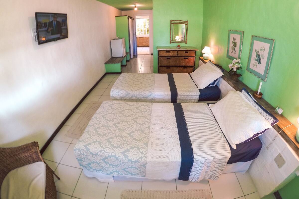 Una habitación con dos camas, un aparador, un espejo y cuadros en la pared.