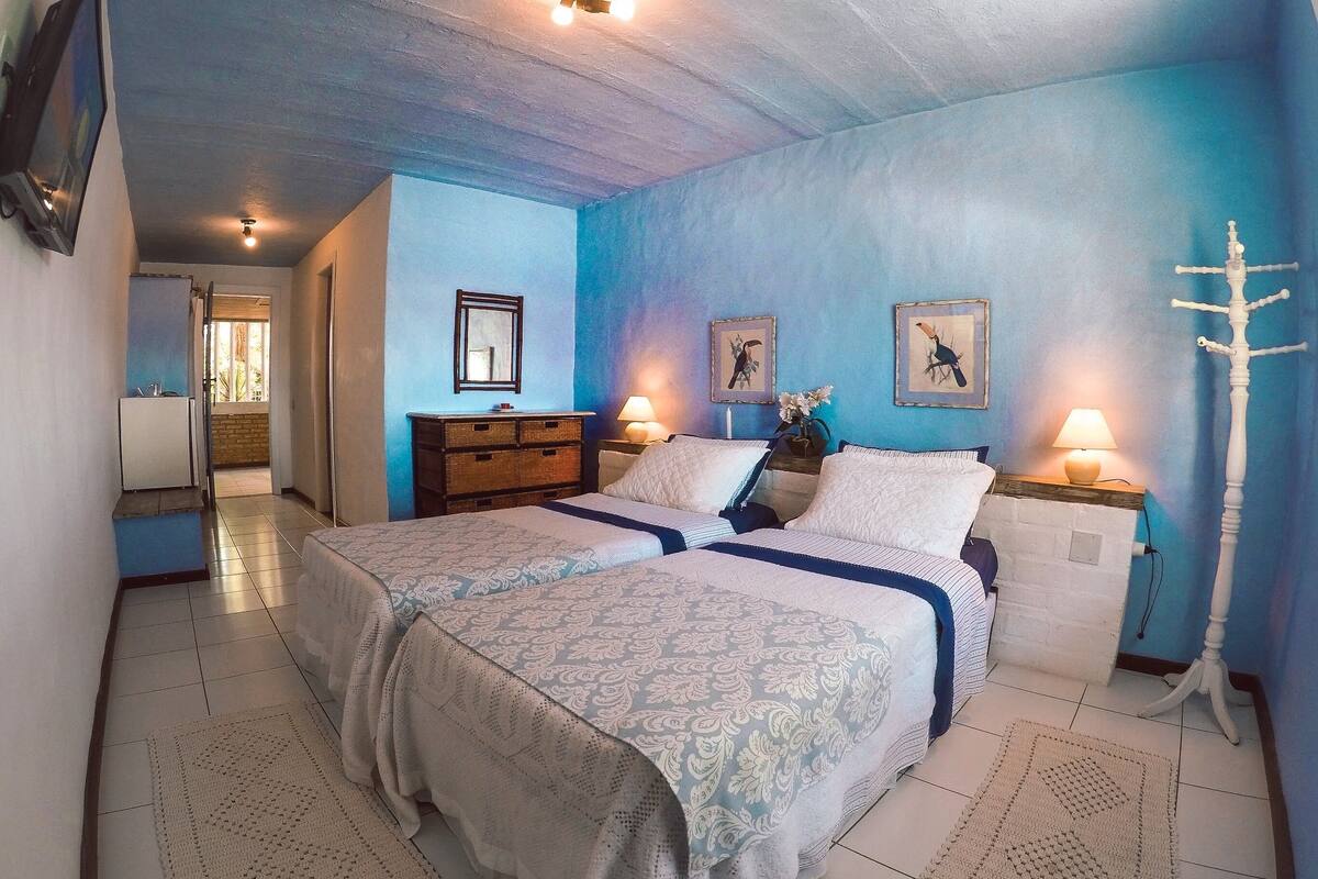 Un dormitorio con dos camas, un aparador y una mesita de noche con lámpara.