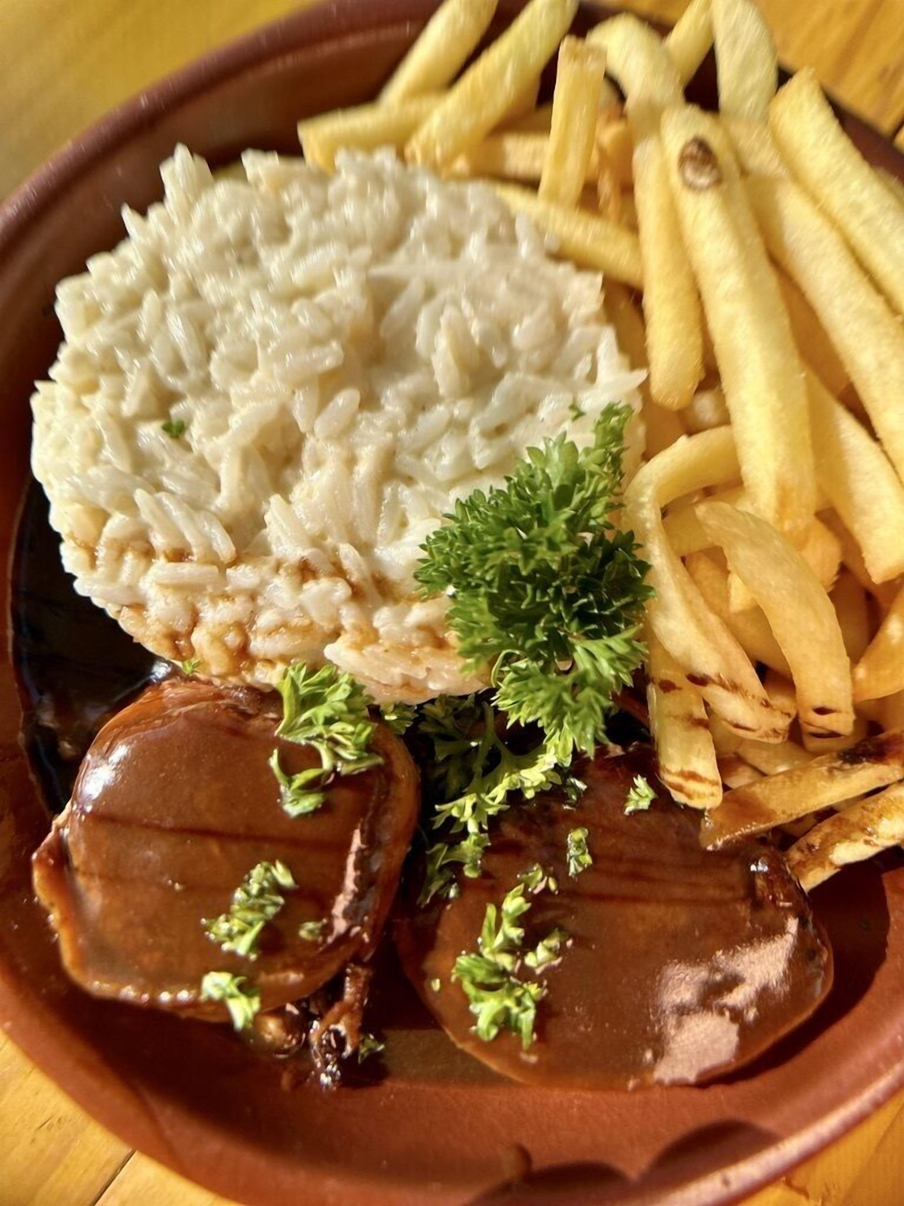 A plate with rice, fries, and a meat dish garnished with parsley.
