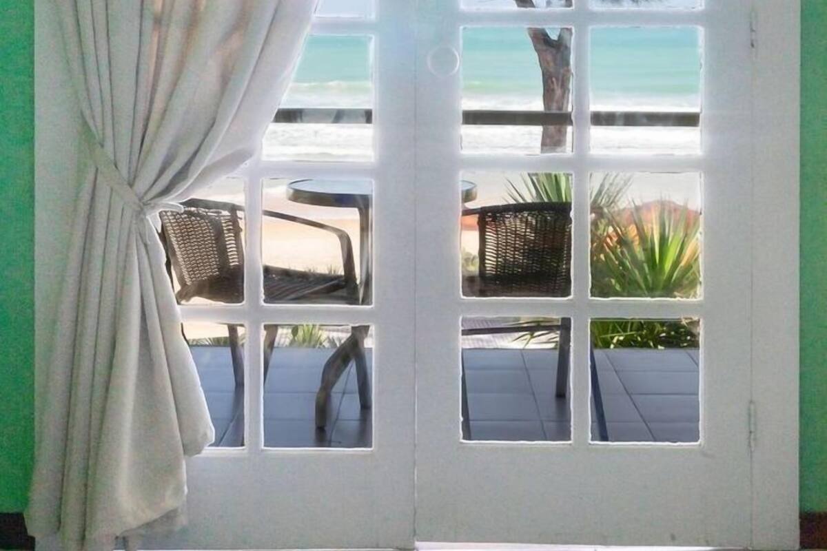 Una habitación con vista al mar, a través de una ventana con cortina.