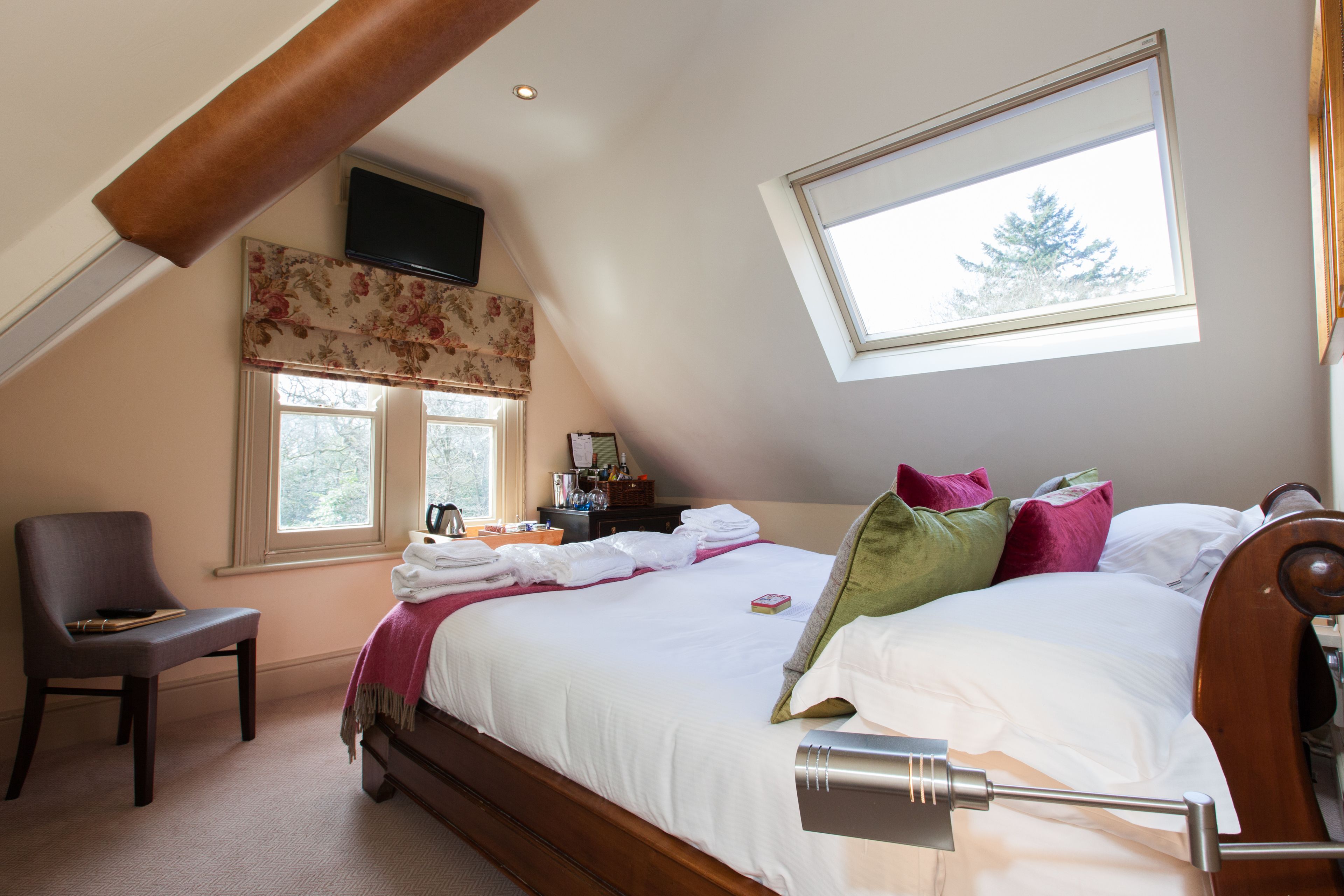 A bedroom with a bed, a chair, a desk, and a window.