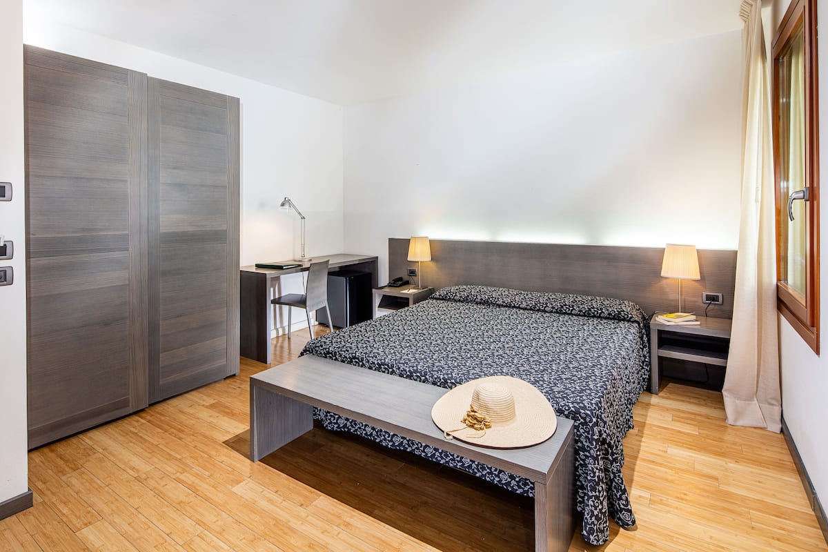 Ein modernes Hotelzimmer mit einem großen Bett, einem Schreibtisch und einem Stuhl.