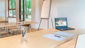 A conference room with a wooden table, a laptop, a flip chart, and a glass of water.