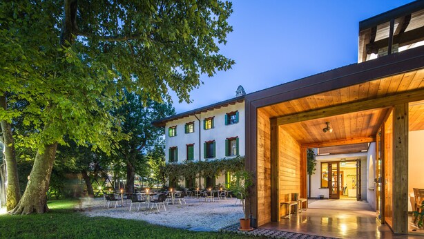 A building with a wooden facade, outdoor seating area, and a well-maintained garden.