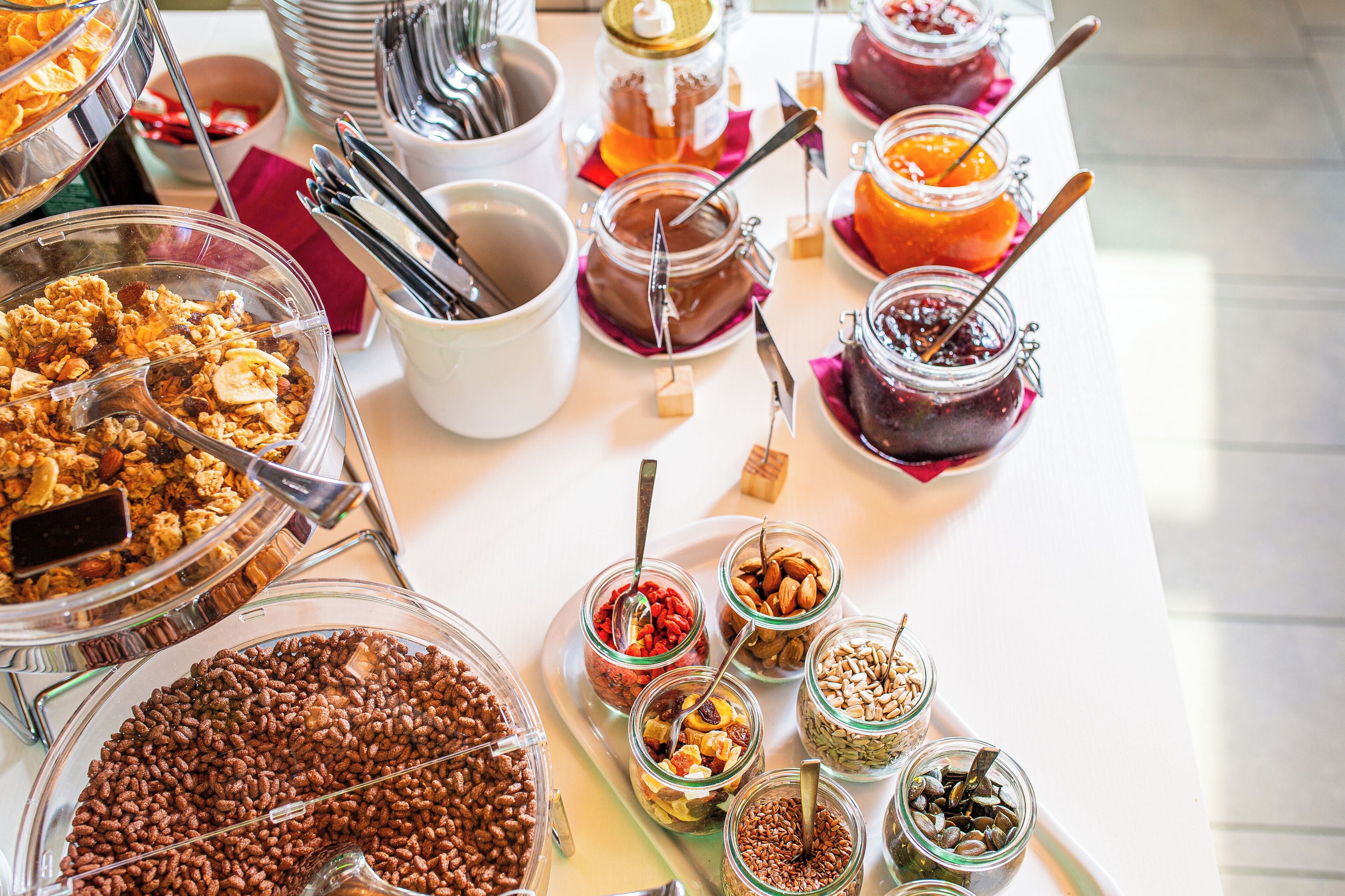 A buffet with various food items including cereals, nuts, and spreads.