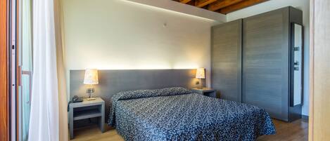 A bedroom with a bed, bedside tables, a wardrobe, and a ceiling with wooden beams.