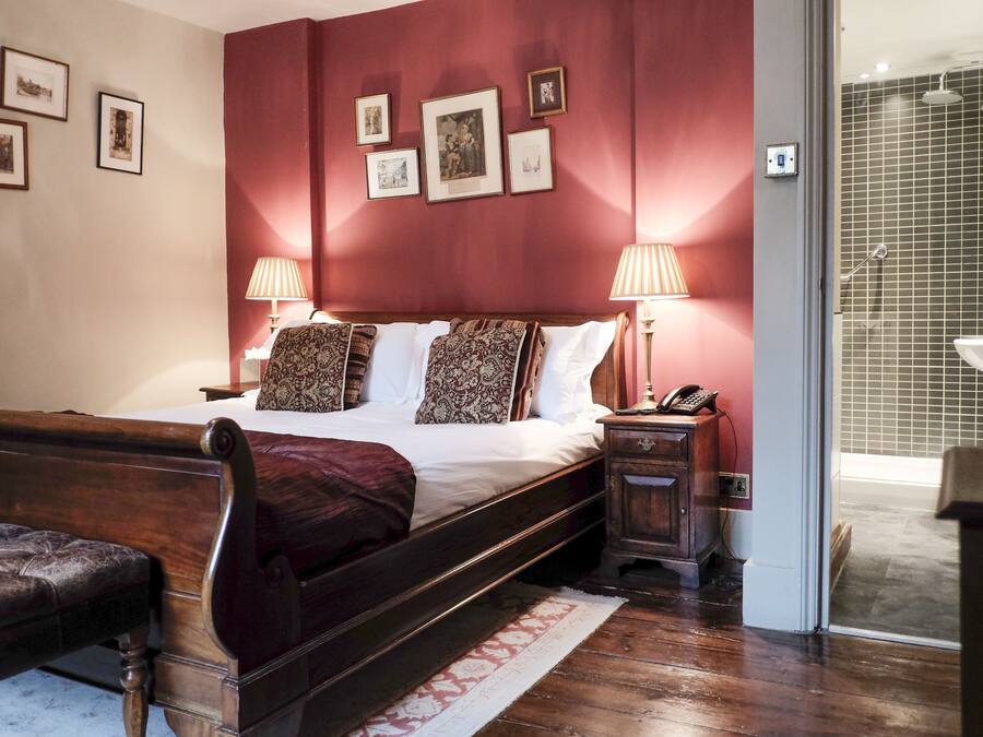 A bedroom with a wooden bed, two bedside lamps, a nightstand, and a bench.