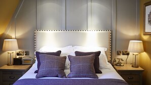 Een hotelkamer met een groot bed, twee nachtkastjes, lampen, een radio en een ingelijst schilderij aan de muur.