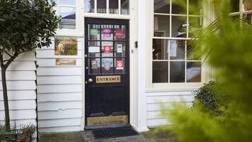 A black entrance door with a 'Welcome to the Wykeham Arms' sign, a 'Hotel Entrance' sign, and various awards and certifications.