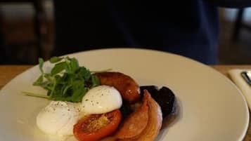 Um prato de comida com ovo escaldado, bacon, tomate e vegetais.