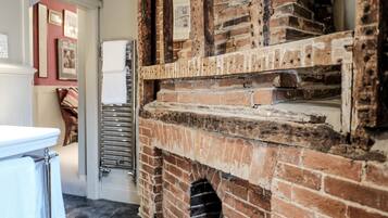 A brick fireplace with a metal shelf, a white radiator, and a door leading to another room.