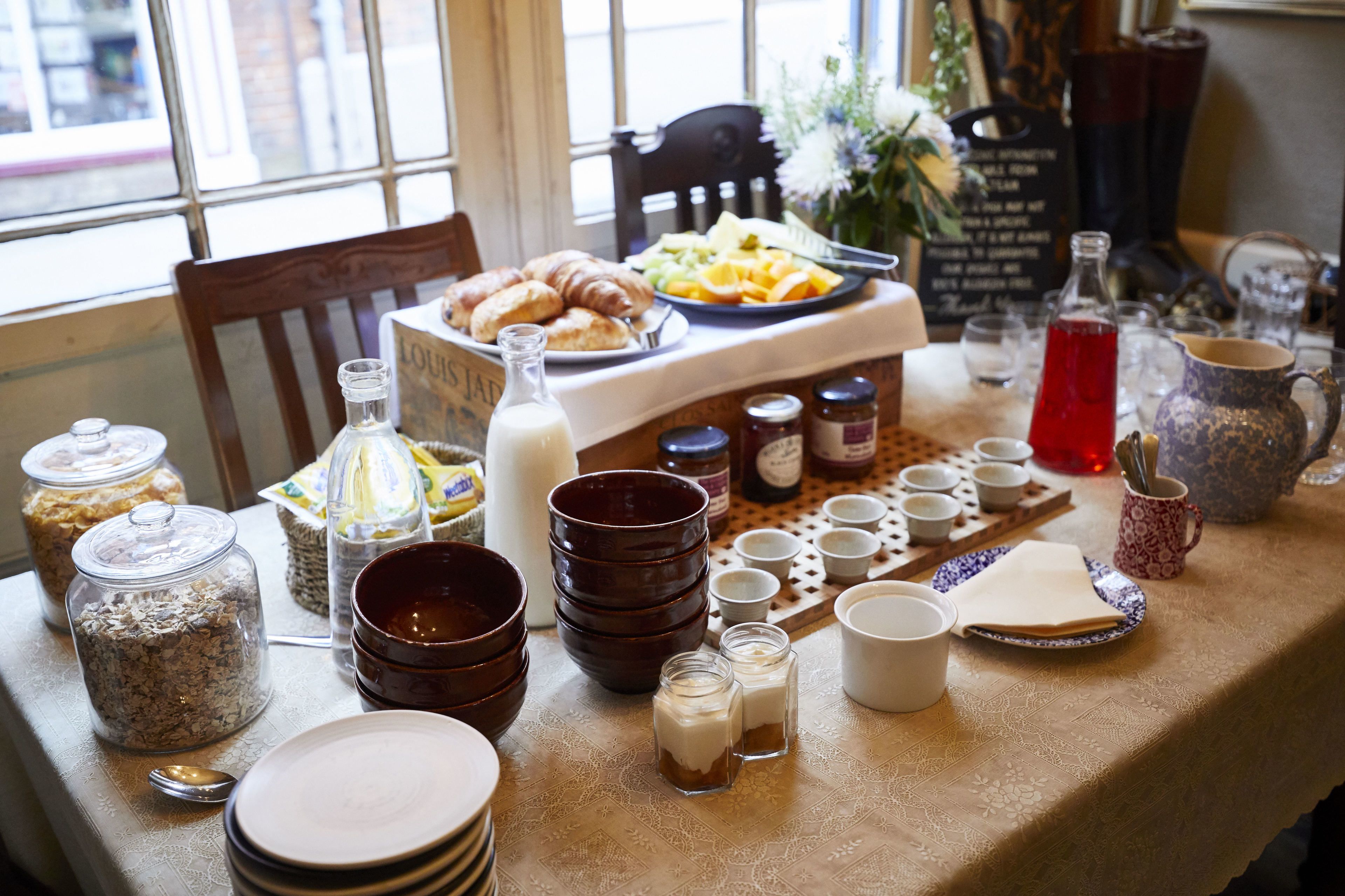 A breakfast table with various food items, jars, and utensils.