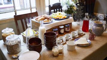 A breakfast table with various food items, jars, and utensils.