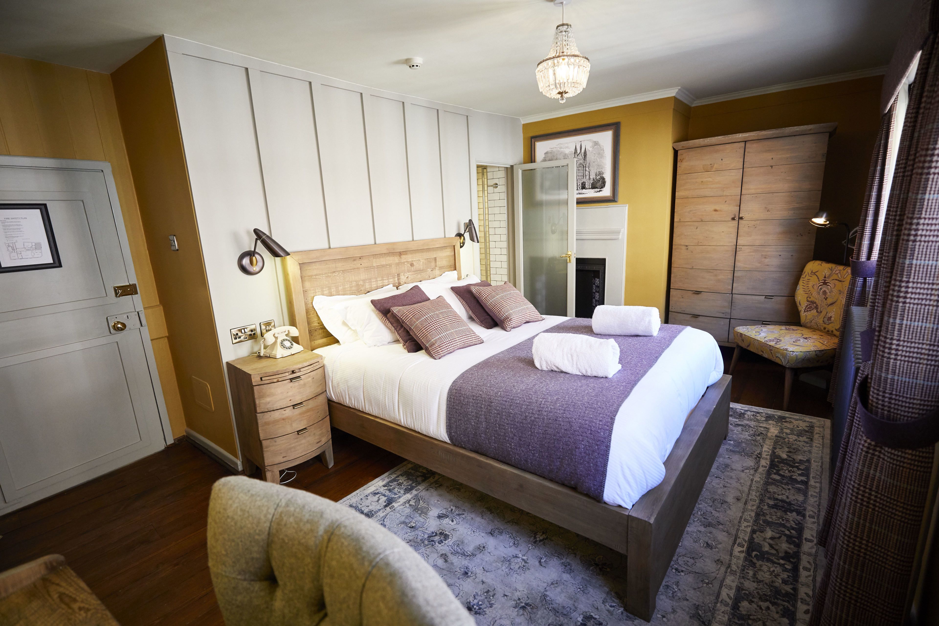 Une chambre à coucher avec un lit en bois, des tables de chevet, une chaise, une armoire et un lustre.