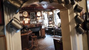 Een interieur met een bar, planken met verschillende spullen en een kroonluchter.