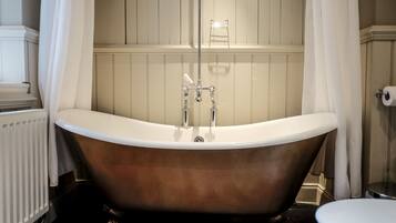 A bathroom with a freestanding bathtub, a toilet, and a radiator.