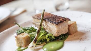 A plate with a piece of meat, greens, and a small bread-like item.