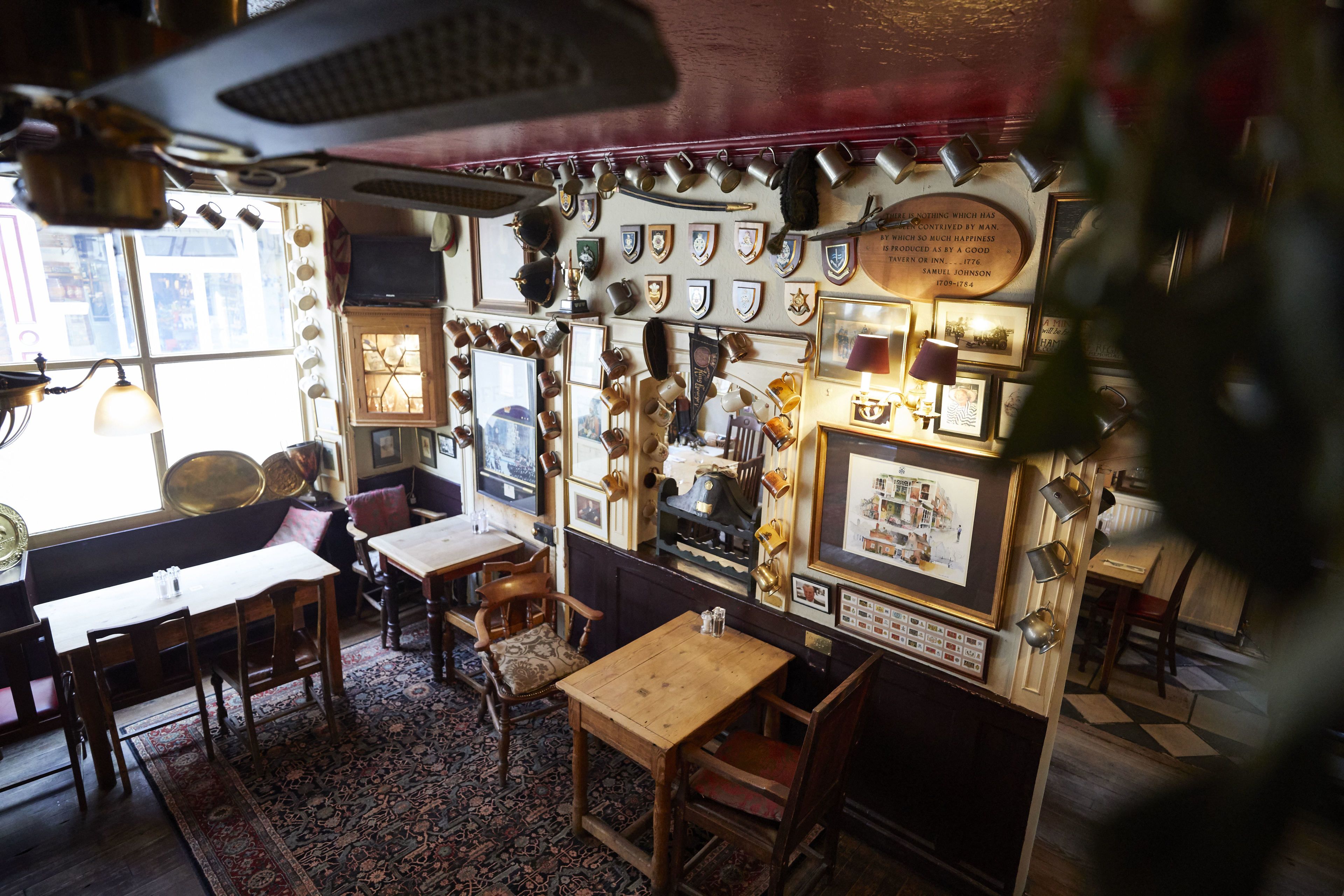 A room with wooden furniture, a patterned rug, and various framed items on the walls.